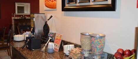 A breakfast bar with a waffle, cereal, and fruit.