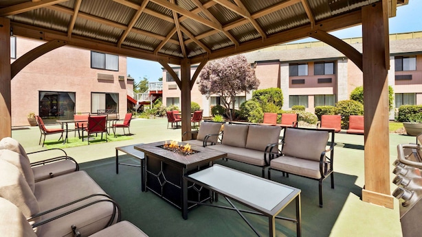 An outdoor patio with a fire pit, seating area, and a covered structure. - Ramada by Wyndham Arcata (Arcata)