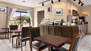 A hotel dining area with a counter, chairs, and a view of the outdoors. - Ramada by Wyndham Arcata (Arcata)