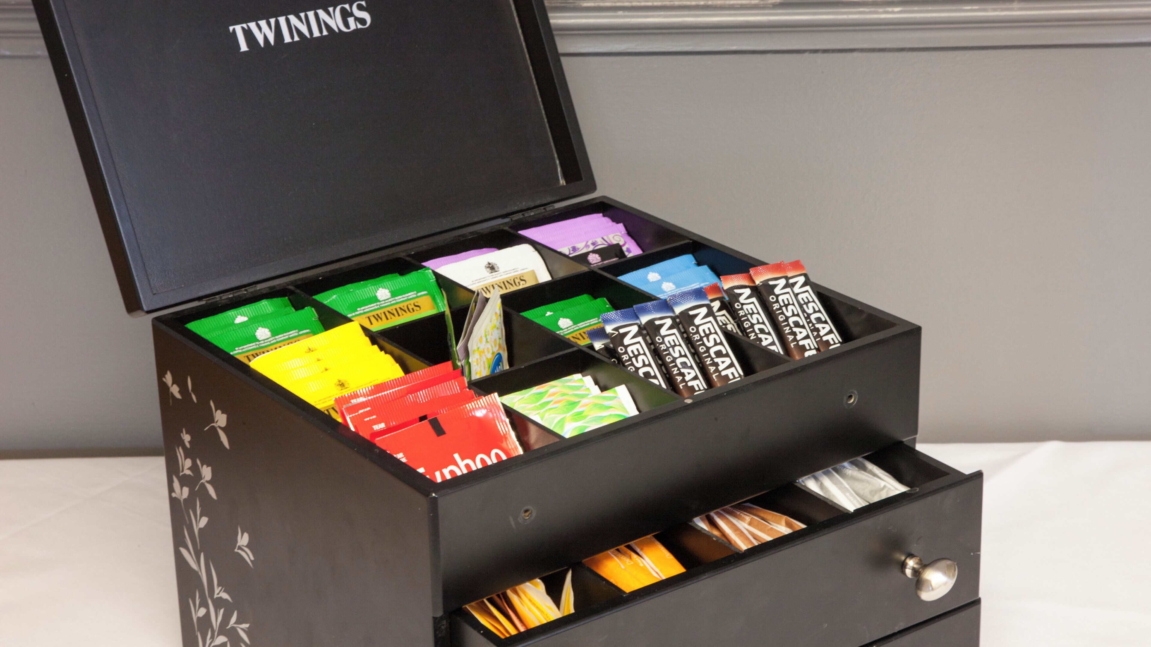 A black box with compartments containing various branded coffee packets.