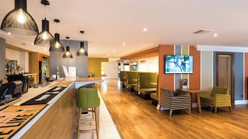 A modern bar area with a wooden counter, bar stools, and pendant lighting.