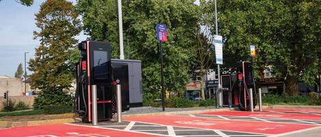 Un espace de stationnement équipé de bornes de recharge pour véhicules électriques, de pistes cyclables clairement délimitées et d’une place de stationnement rouge.