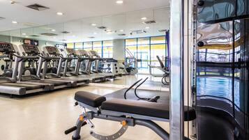 A gym with treadmills, weight machines, and a large mirror.