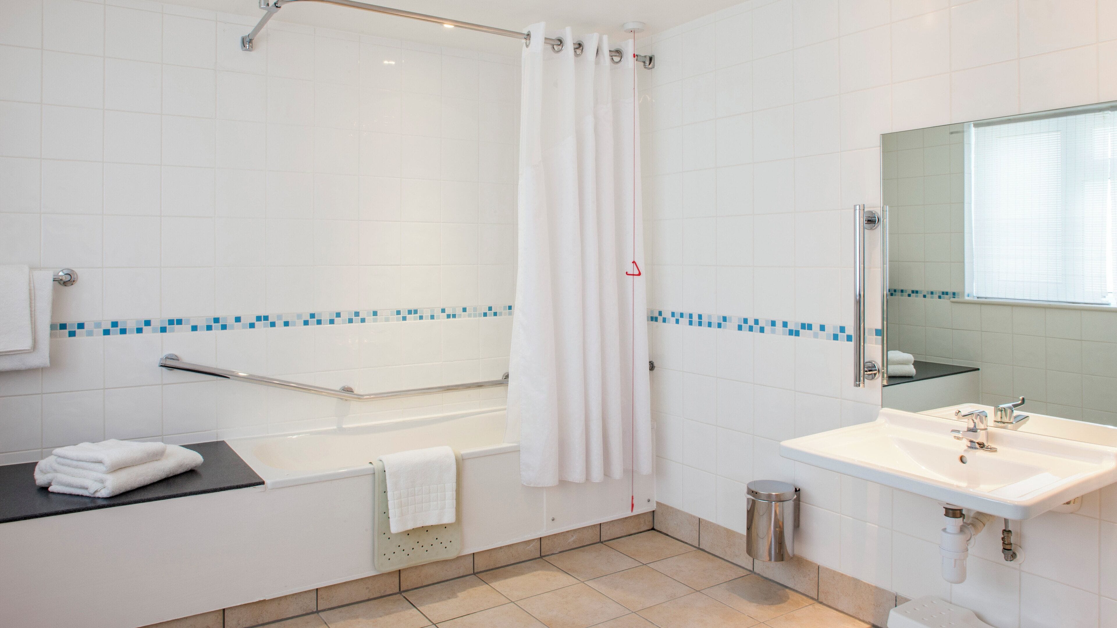 A modern bathroom with a bathtub, shower, and sink.