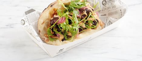 A flatbread with toppings on a white surface.
