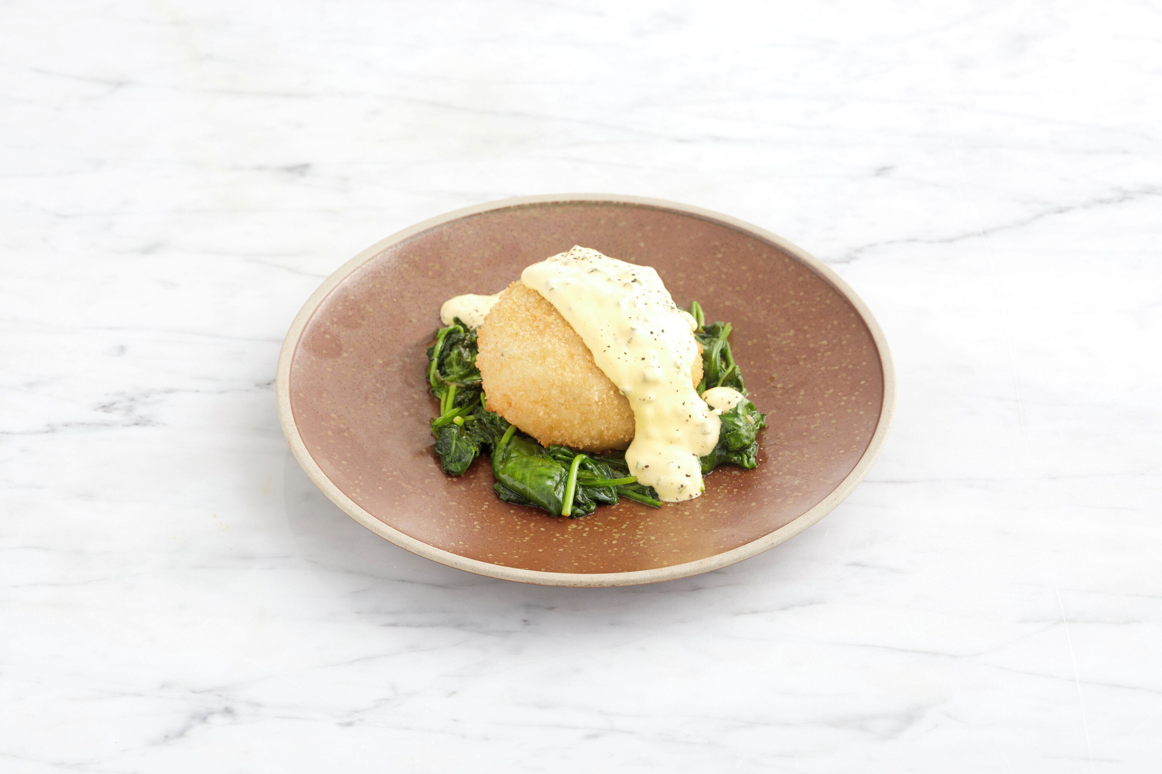 A plate with a food item on a marble surface.