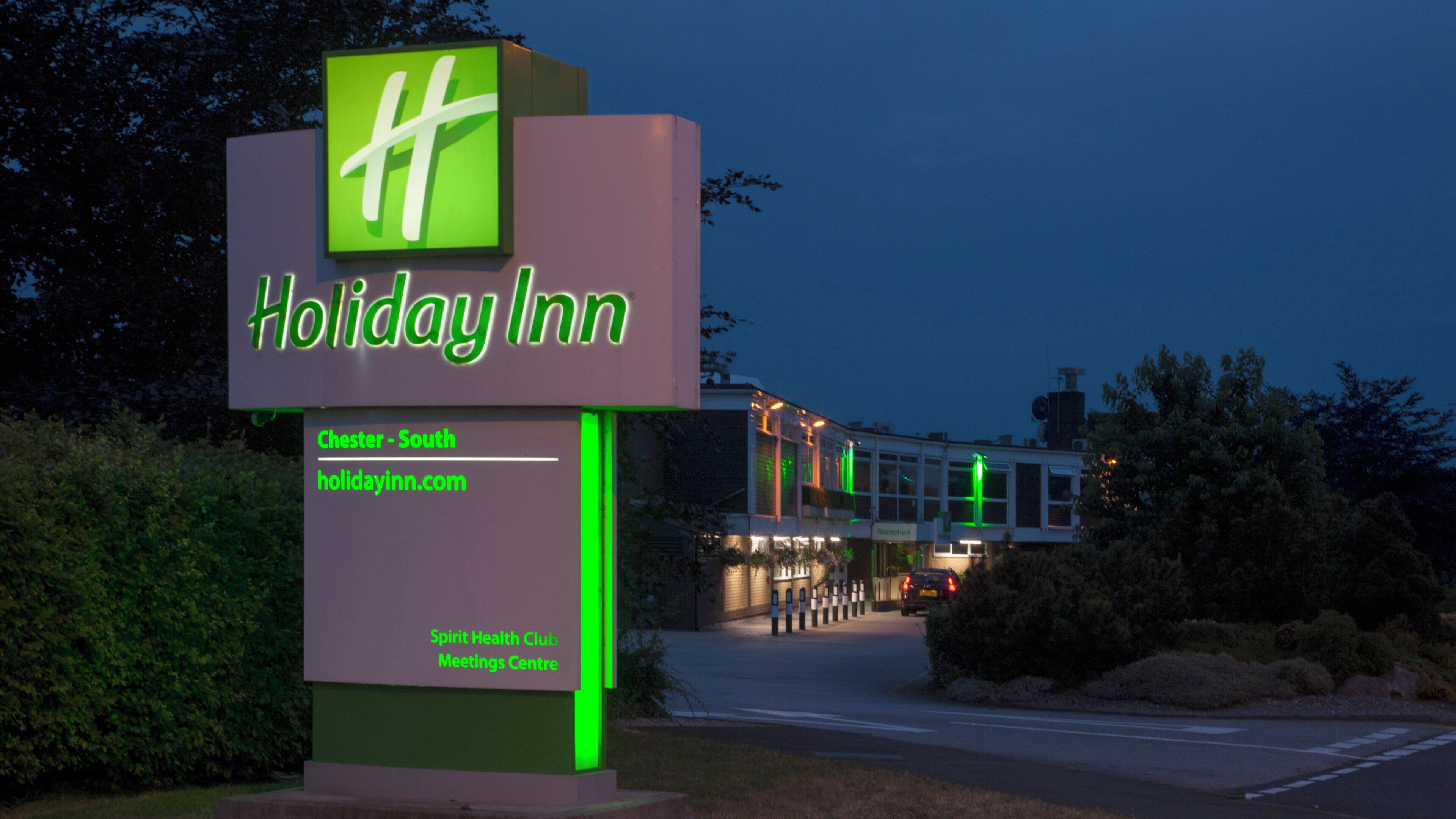 Señal de Holiday Inn con logotipo verde, una dirección web y referencia a Spirit Health Club Meetings Centre.