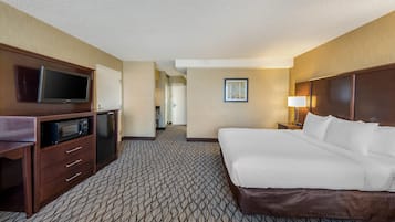 A hotel room with a bed, a television, a microwave, a desk, and a door leading to a hallway.
