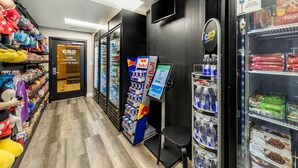 A corridor with shelves stocked with snacks, a Red Bull vending machine, and a Coca-Cola refrigerator.