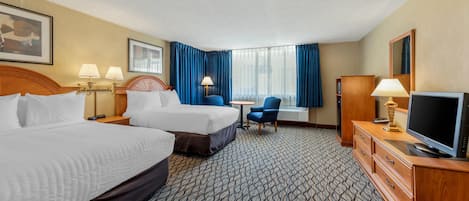 A hotel room with two beds, a desk, a chair, a TV, and a wardrobe.