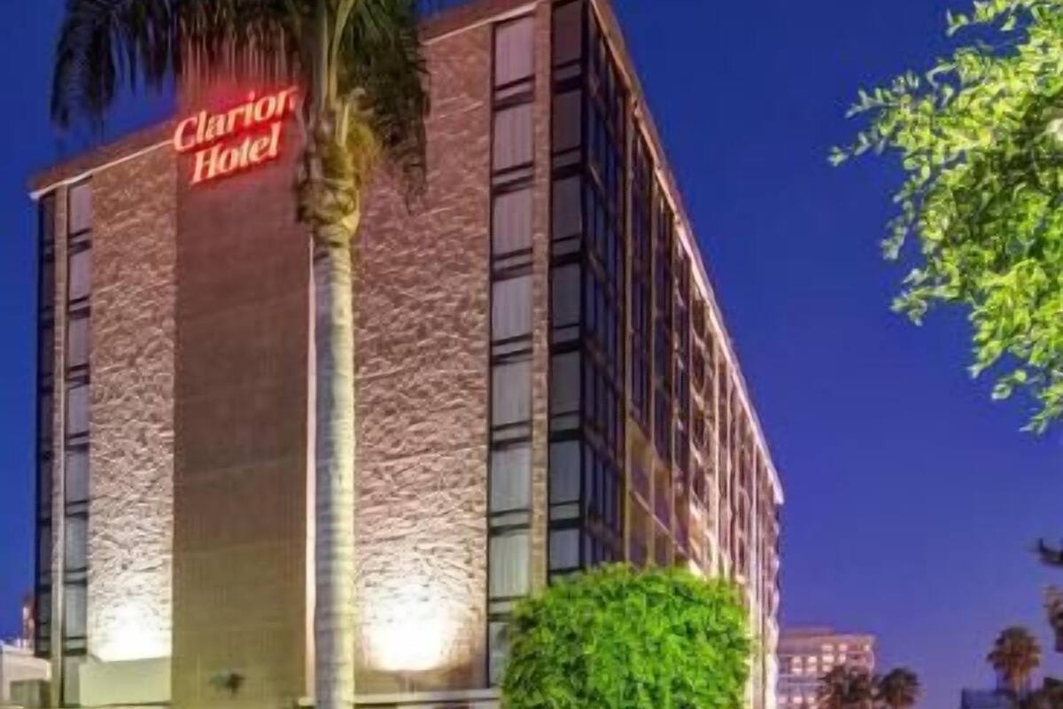 A hotel building with a prominent sign, a well-maintained lawn, and a clear sky.