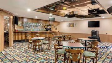 Un restaurant doté d’un sol à motifs, de tables et de chaises en bois, d’un bar et d’un téléviseur fixé au mur.