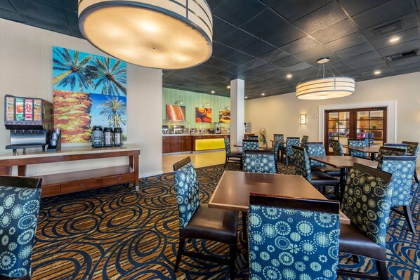 A restaurant with patterned chairs, a counter with food displays, and a menu board.