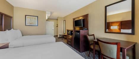 Una habitación de hotel con una cama grande, un escritorio con silla, televisión y espejo.
