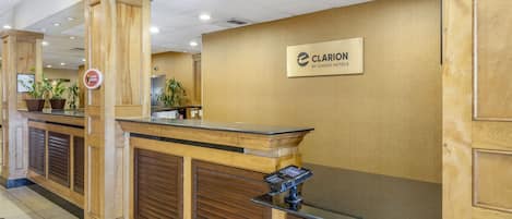 A reception desk with a wooden finish, a sign for Clarion by Choice Hotels, and a security keypad.