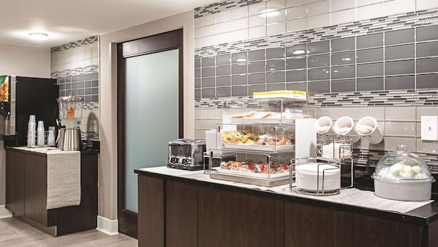 A modern kitchen with a built-in coffee station, a toaster, and a variety of food items on display.