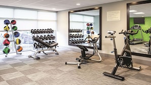 A gym with exercise equipment, weight racks, and a large mirror.