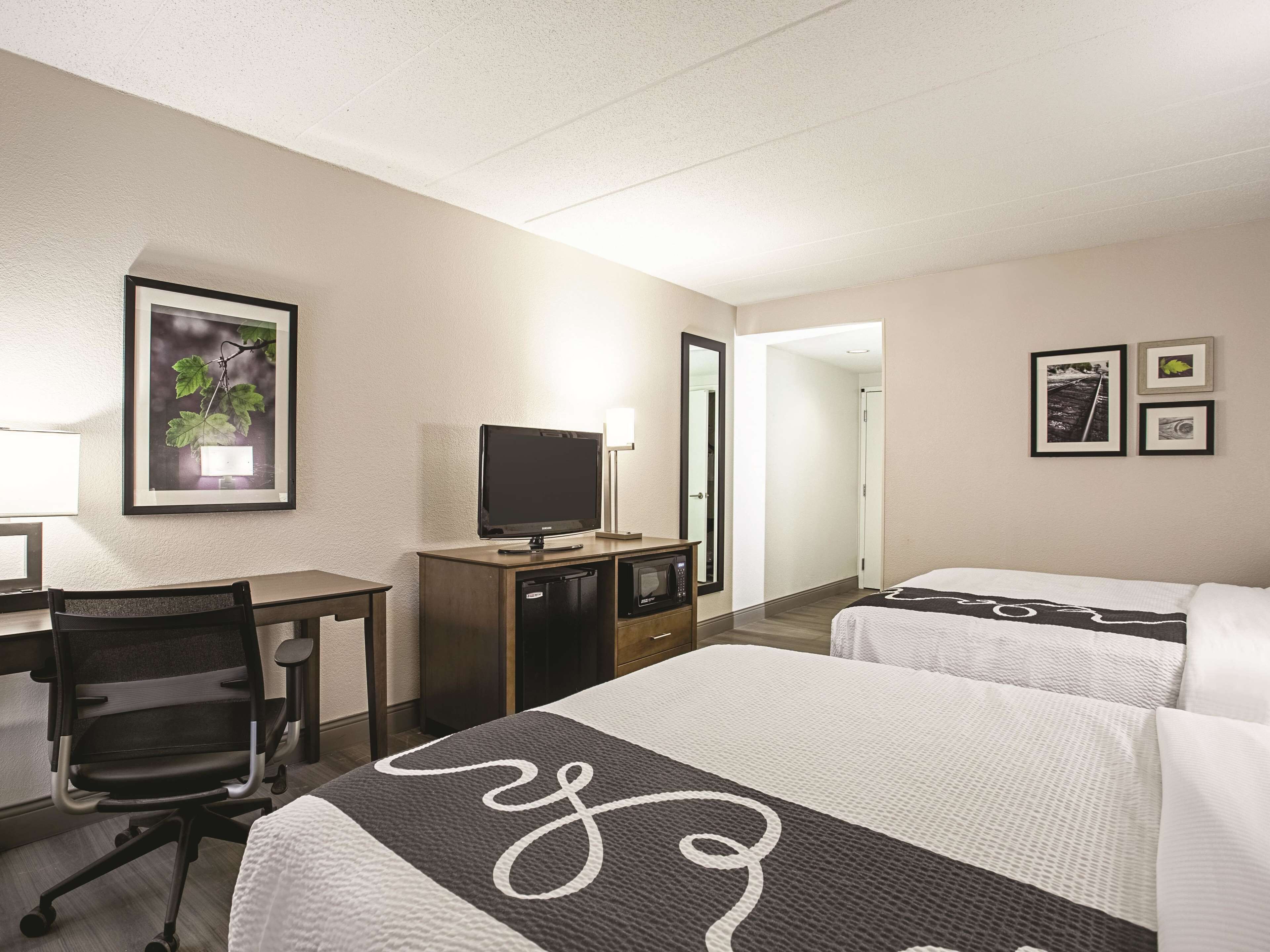 Una habitación de hotel con escritorio, televisión, cama con colcha y espejo.