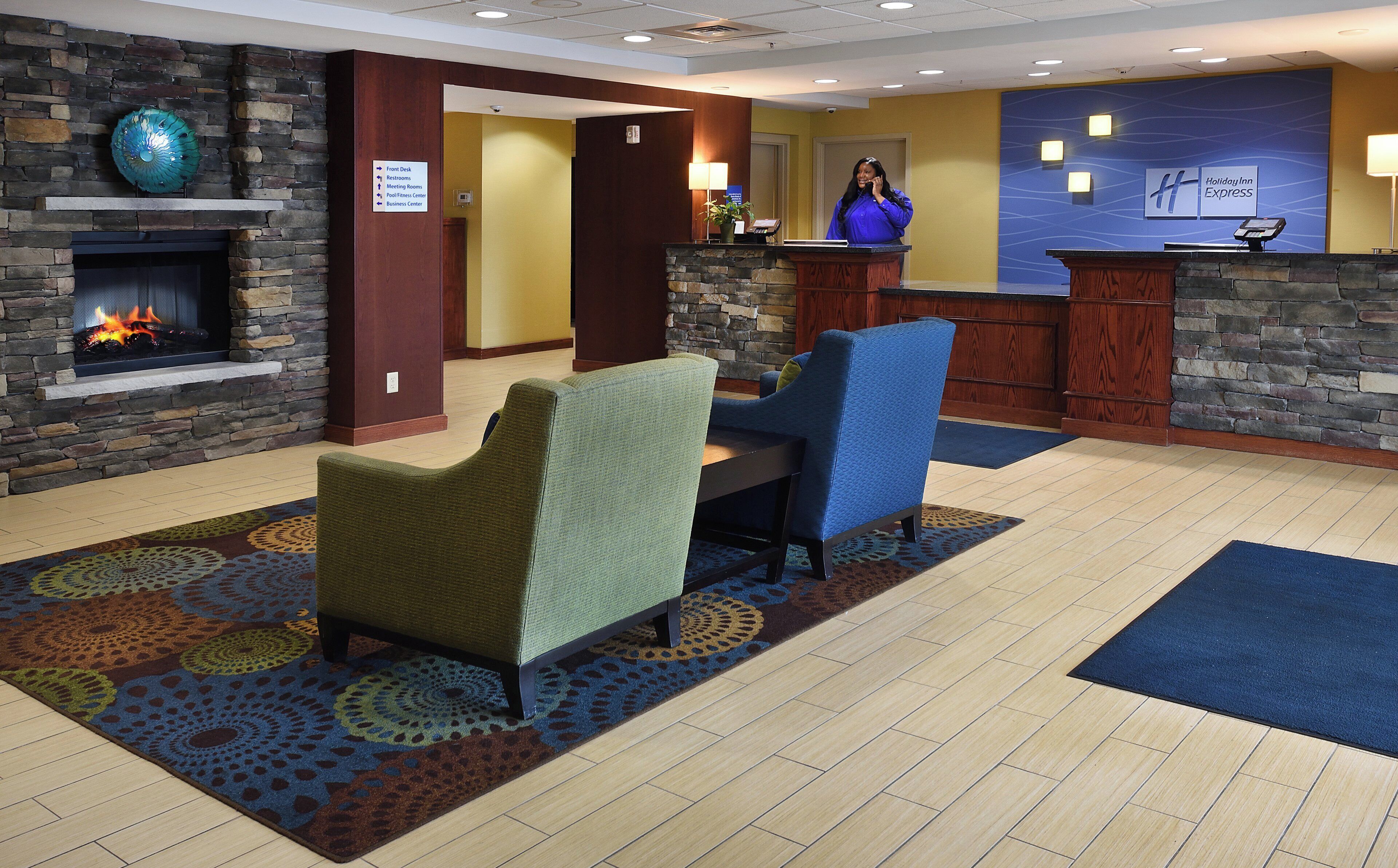 A lobby with a reception desk, a fireplace, and seating area.