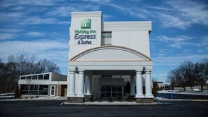 Edificio de Holiday Inn Express & Suites con diseño arquitectónico moderno, que destaca por una entrada prominente con columnas y un amplio frente de vidrio.