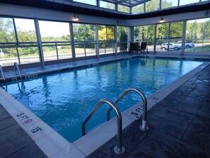 Una piscina interior con paredes de vidrio transparente, una silla de salvavidas y una escalera de natación.
