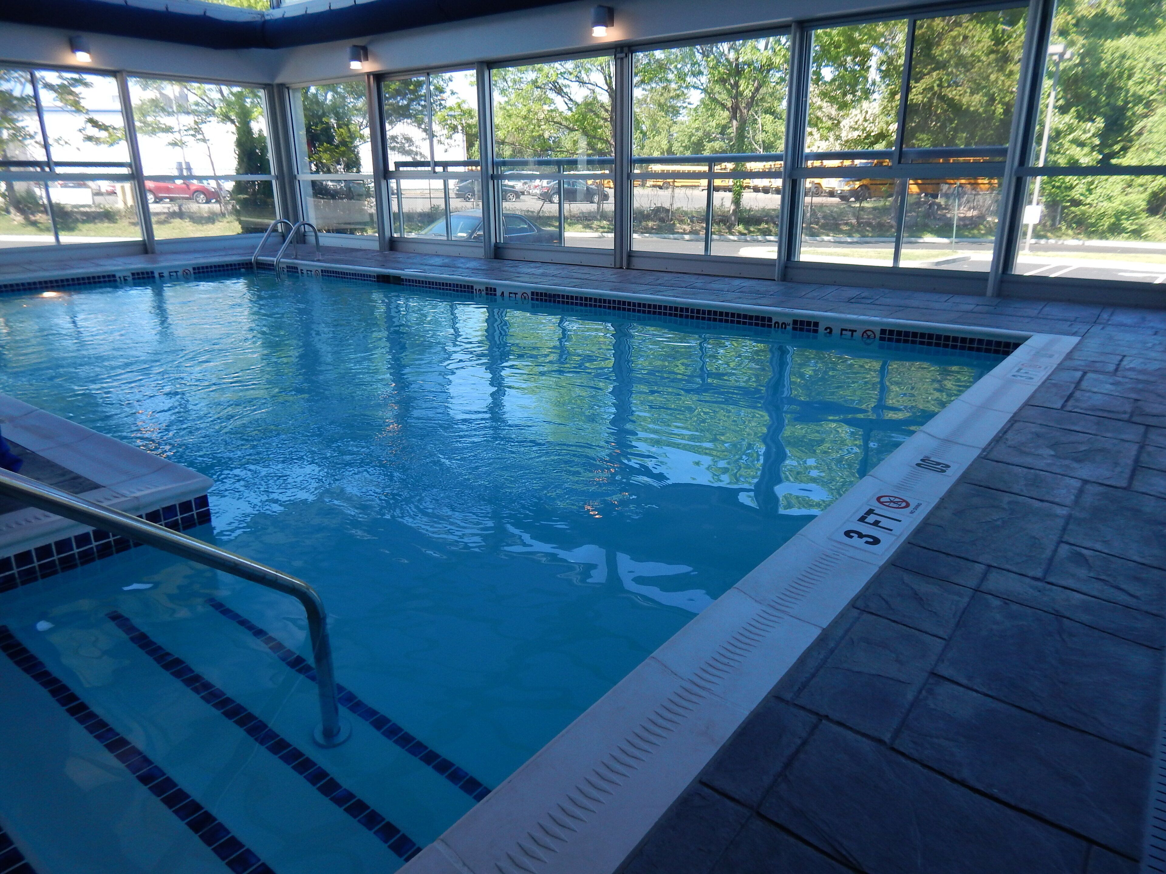 An indoor swimming pool with clear water, a diving board, and a tiled deck.