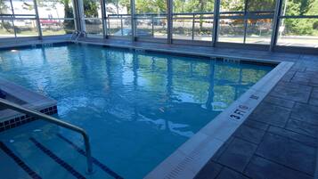 An indoor swimming pool with clear water, a diving board, and a tiled deck.