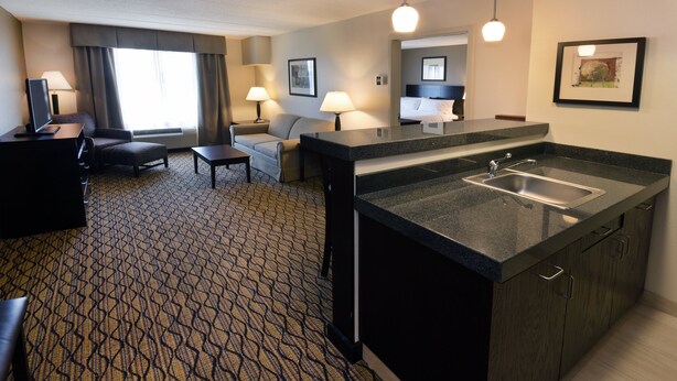 Una habitación de hotel con kitchenette, sofá, escritorio y cama.