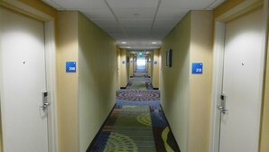 Un pasillo de hotel con puertas numeradas 208 y 213, cubierto de alfombra con un estampado geométrico de colores.