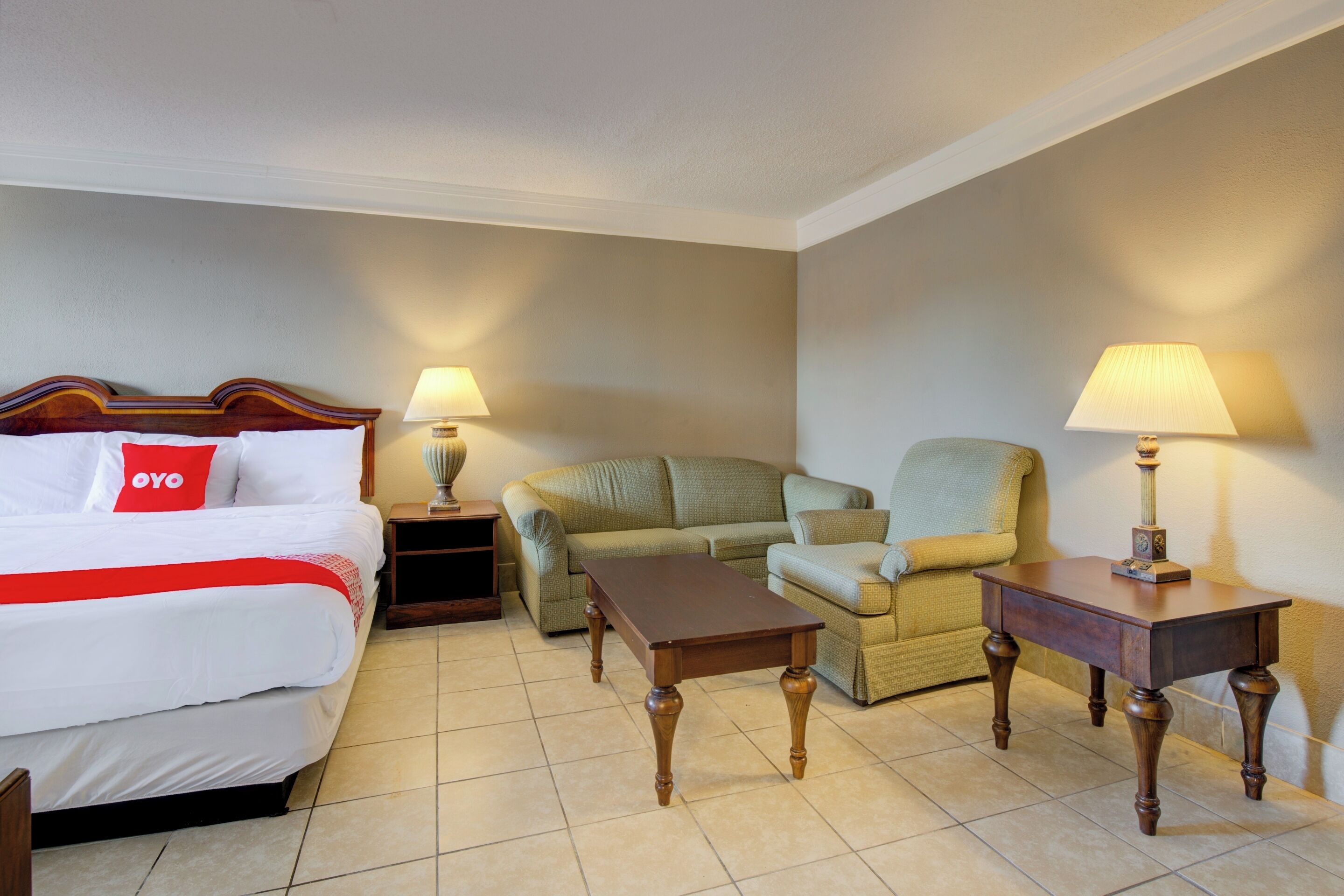 Une chambre d’hôtel avec un lit, un canapé, une petite table et deux lampes.