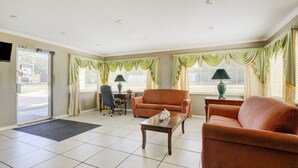 A spacious room with a large window, a sofa, a coffee table, and a desk with a chair. -  Hotel Douglas GA US-441 (Douglas)