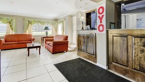 A living room with a sofa, armchair, and coffee table. There is a fireplace with a wooden cabinet and a sign that reads "OYO". -  Hotel Douglas GA US-441 (Douglas)