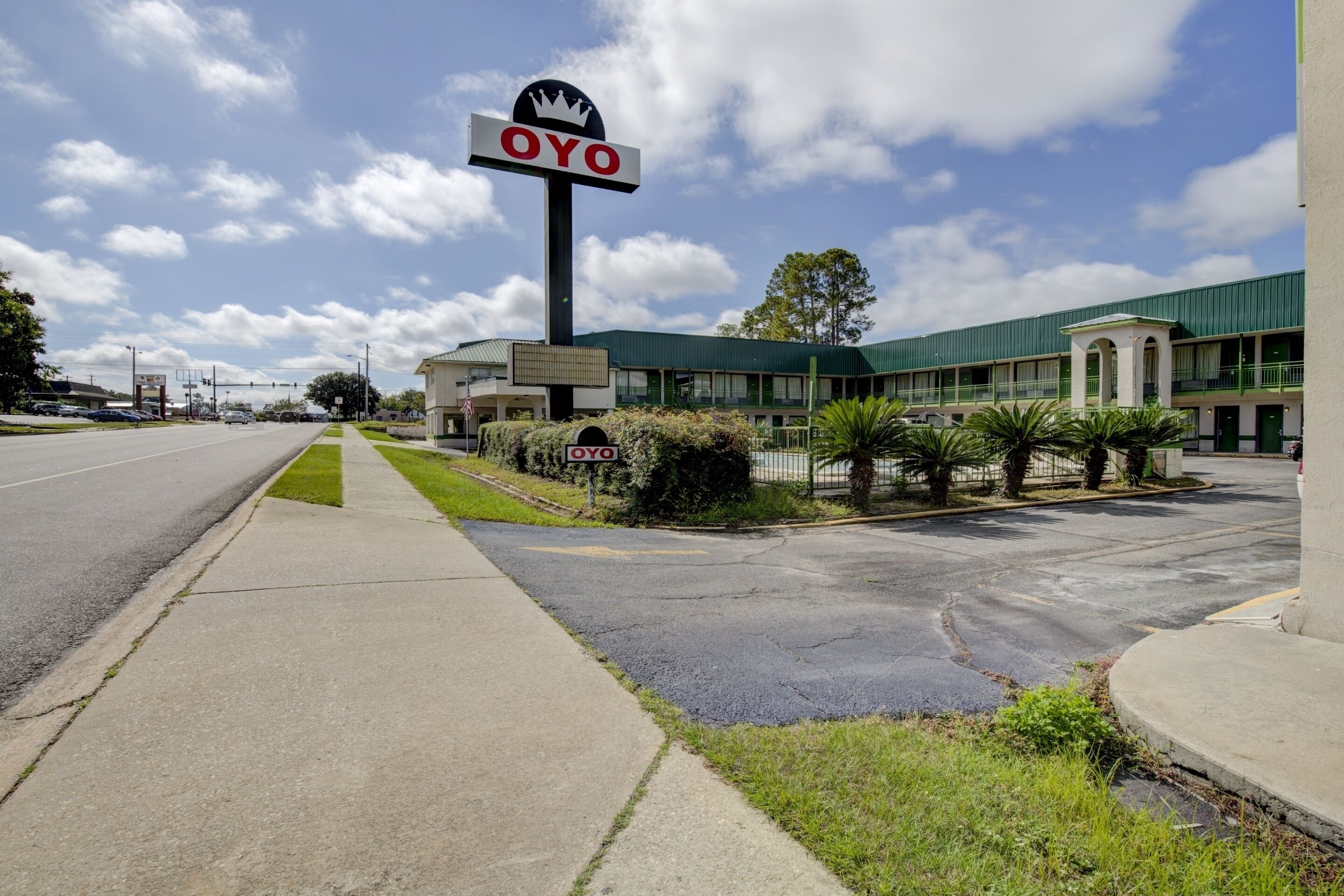 A hotel with a prominent 'OYO' sign, a parking lot, and a building with a green roof.
