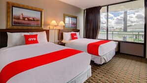 A hotel room with two beds, each with a red and white bedspread, a large window with a view of a cityscape, and two wall-mounted lamps. -  Hotel Douglas GA US-441 (Douglas)