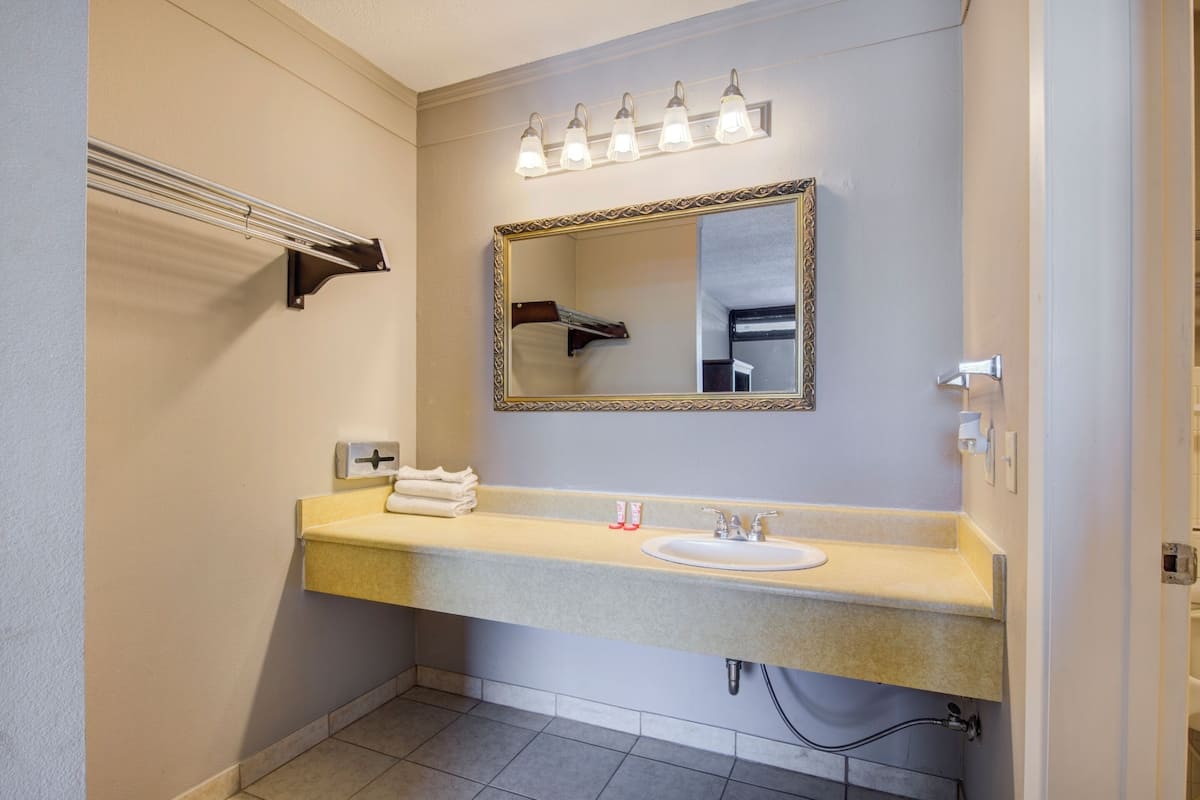 Un baño con lavamanos, espejo, toallero e iluminación.