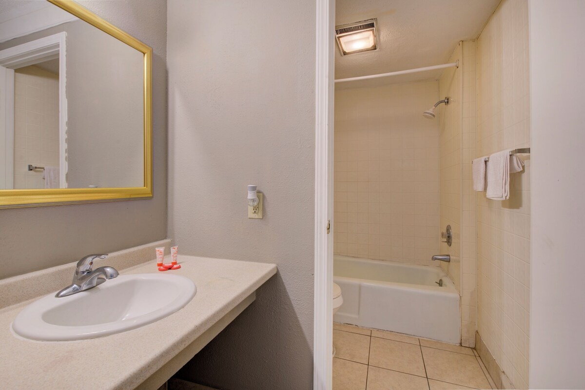 A bathroom with a sink, mirror, and bathtub.