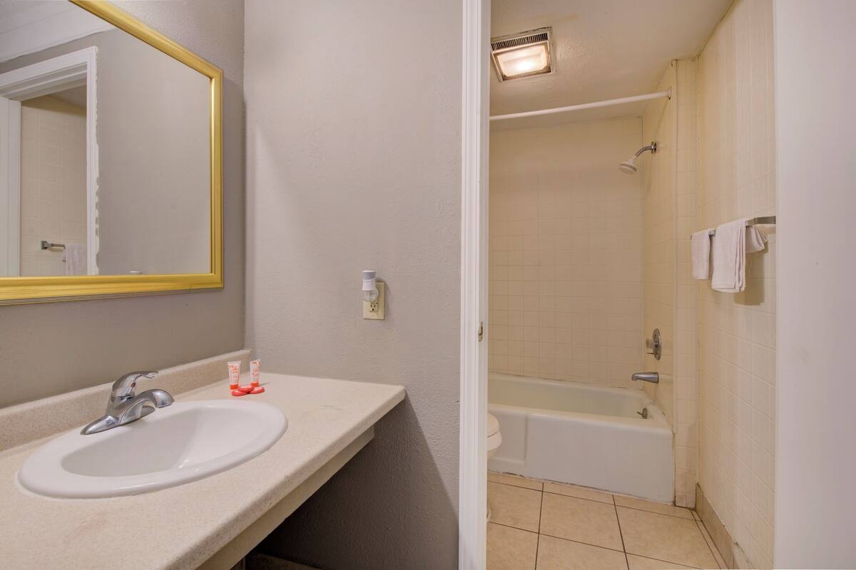 A bathroom with a sink, mirror, and bathtub.
