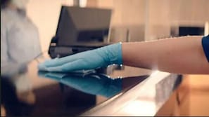 A hand wearing a blue glove cleaning a reflective surface, likely a table or counter. - Quality Inn West Plano - Dallas (Plano)