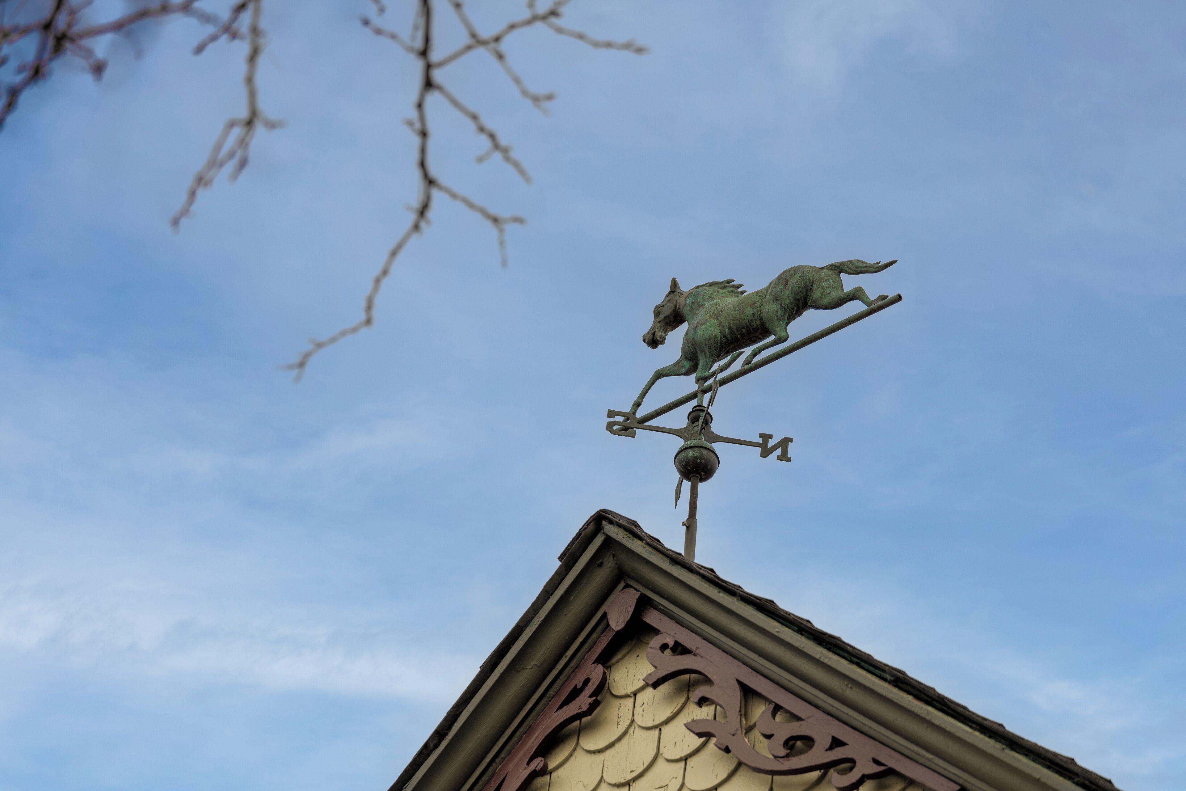 A weather vane with a horse design on a building's roof.