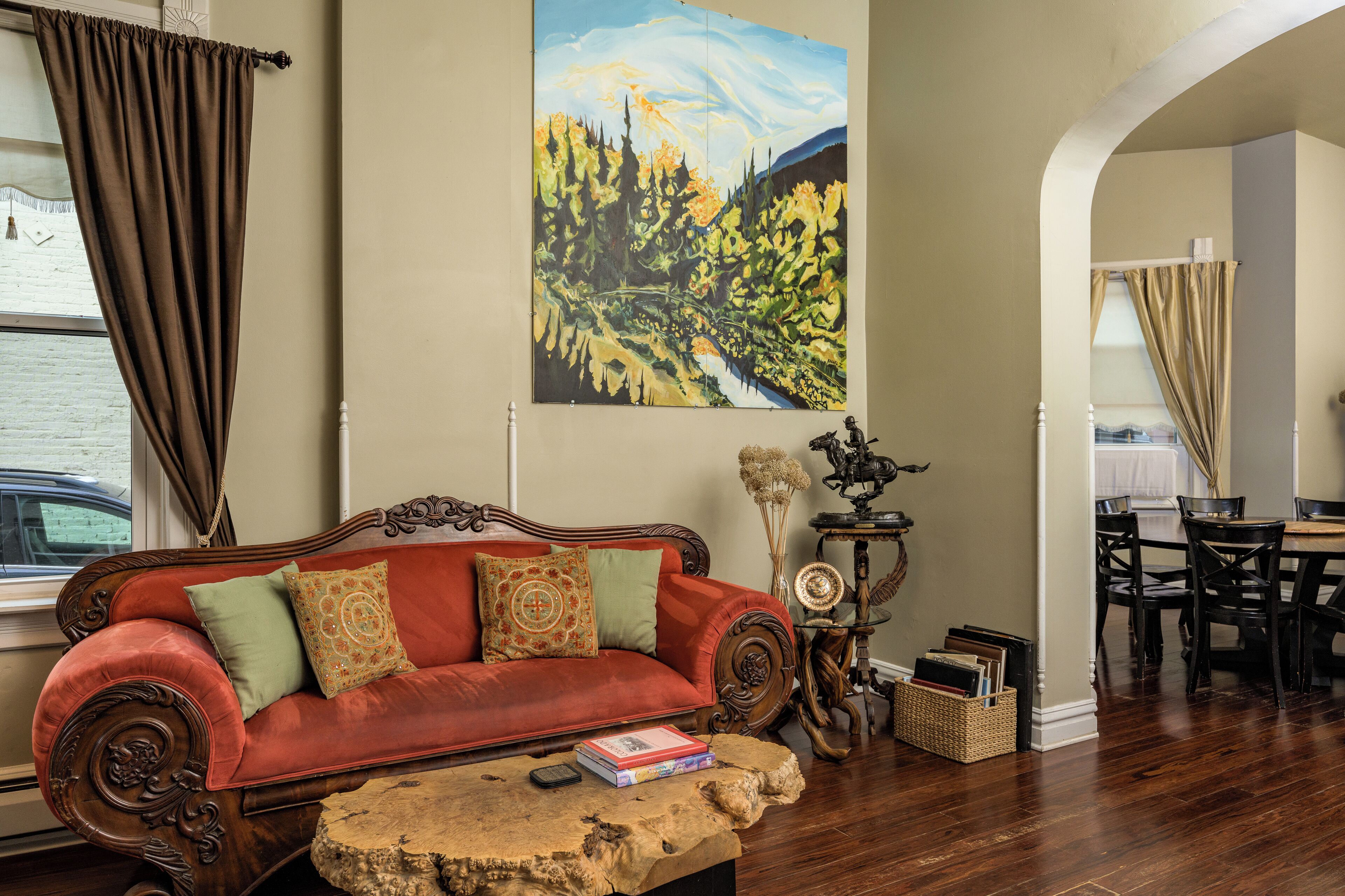 A living room with a red sofa, wooden coffee table, and a painting of a landscape.