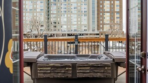 A view from a balcony with a hot tub, a wooden deck, and a cityscape with tall buildings in the background. - Queen Anne Bed And Breakfast (Denver)