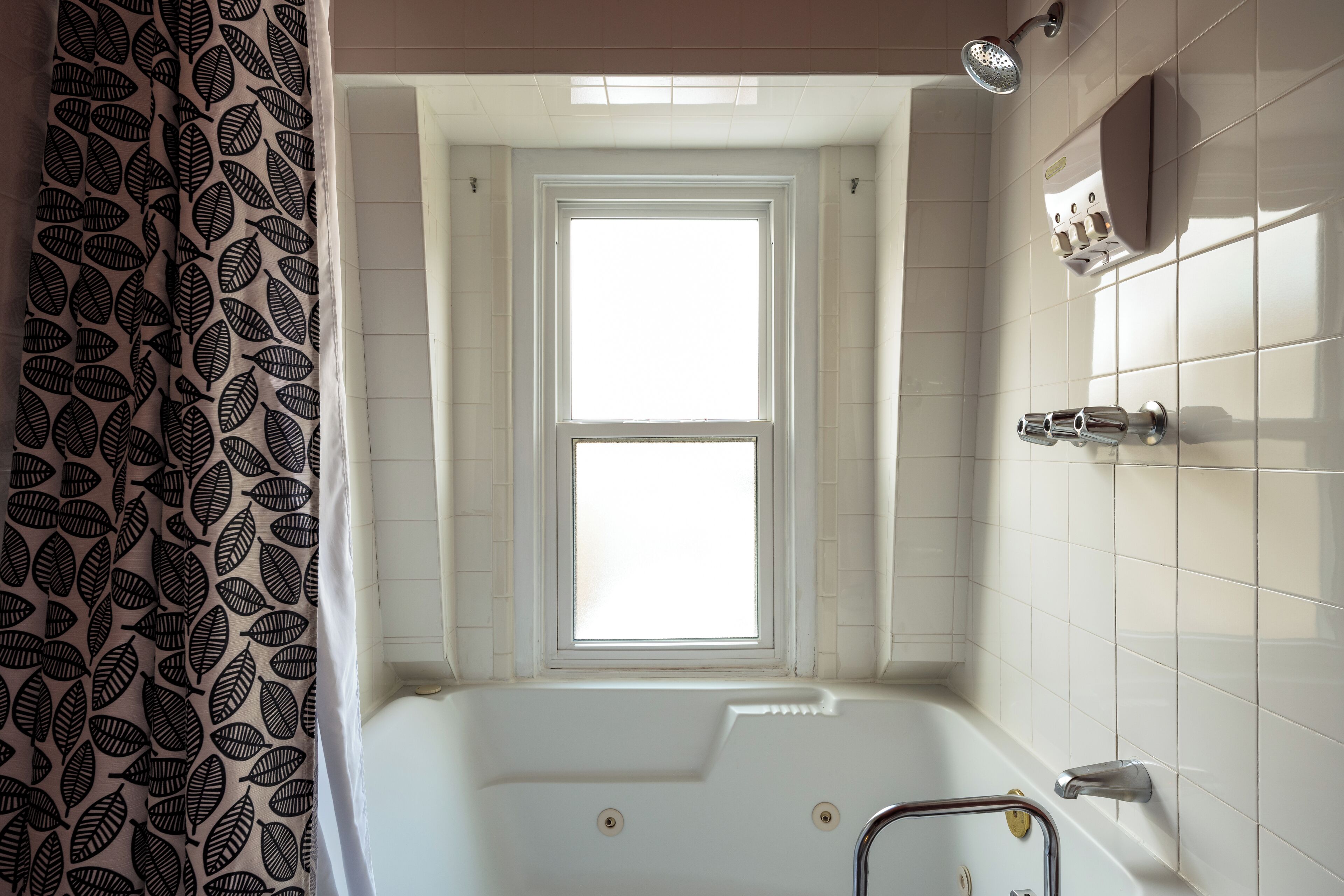 Une salle de bain avec une baignoire, une fenêtre et un pommeau de douche.
