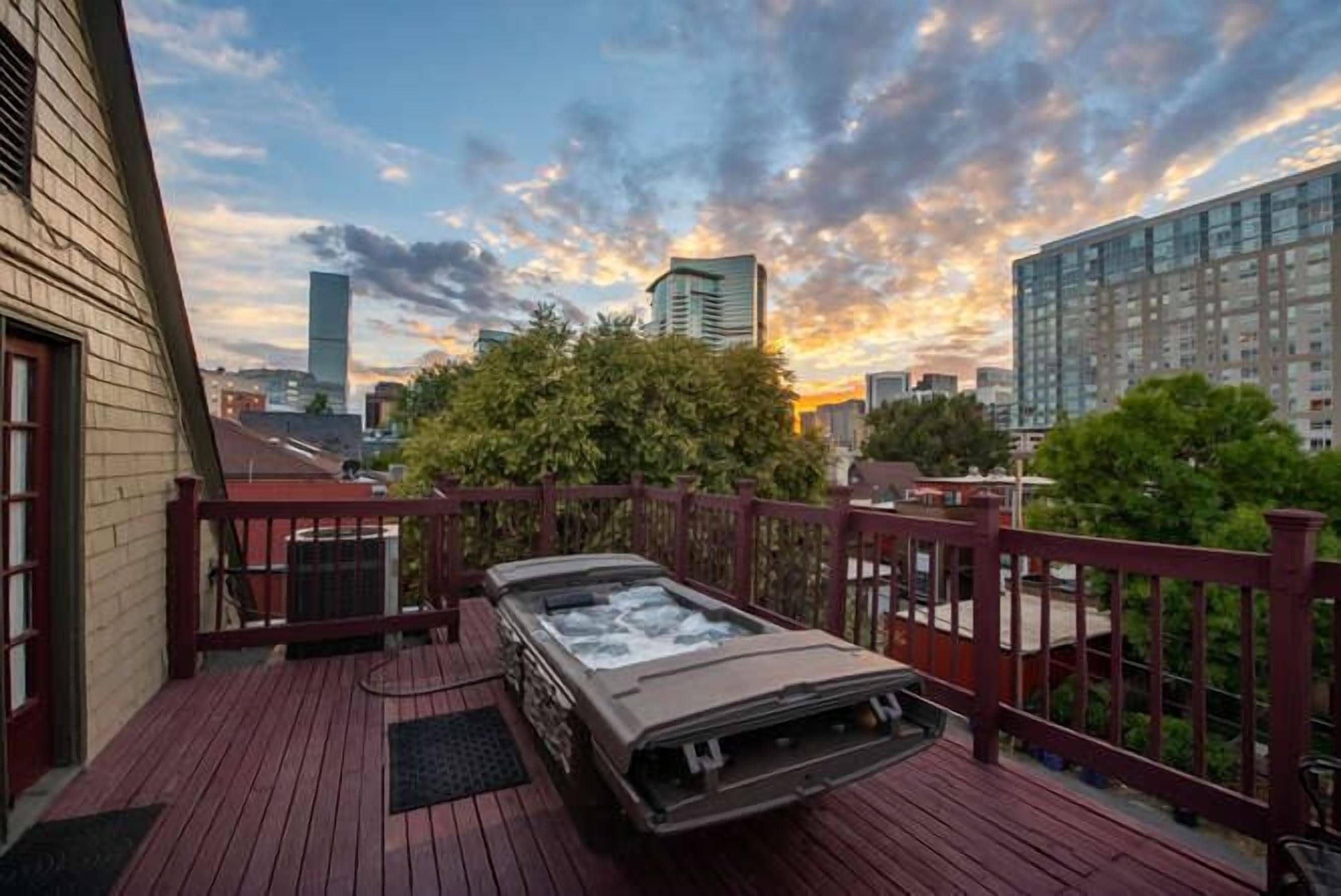 Un jacuzzi en una terraza de madera con el horizonte de la ciudad al fondo.