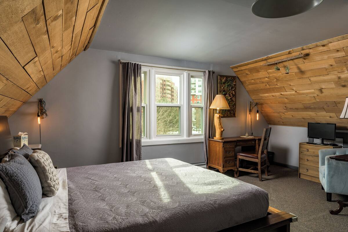 Une chambre à coucher comprenant un lit, un bureau, une chaise, une commode et un téléviseur.