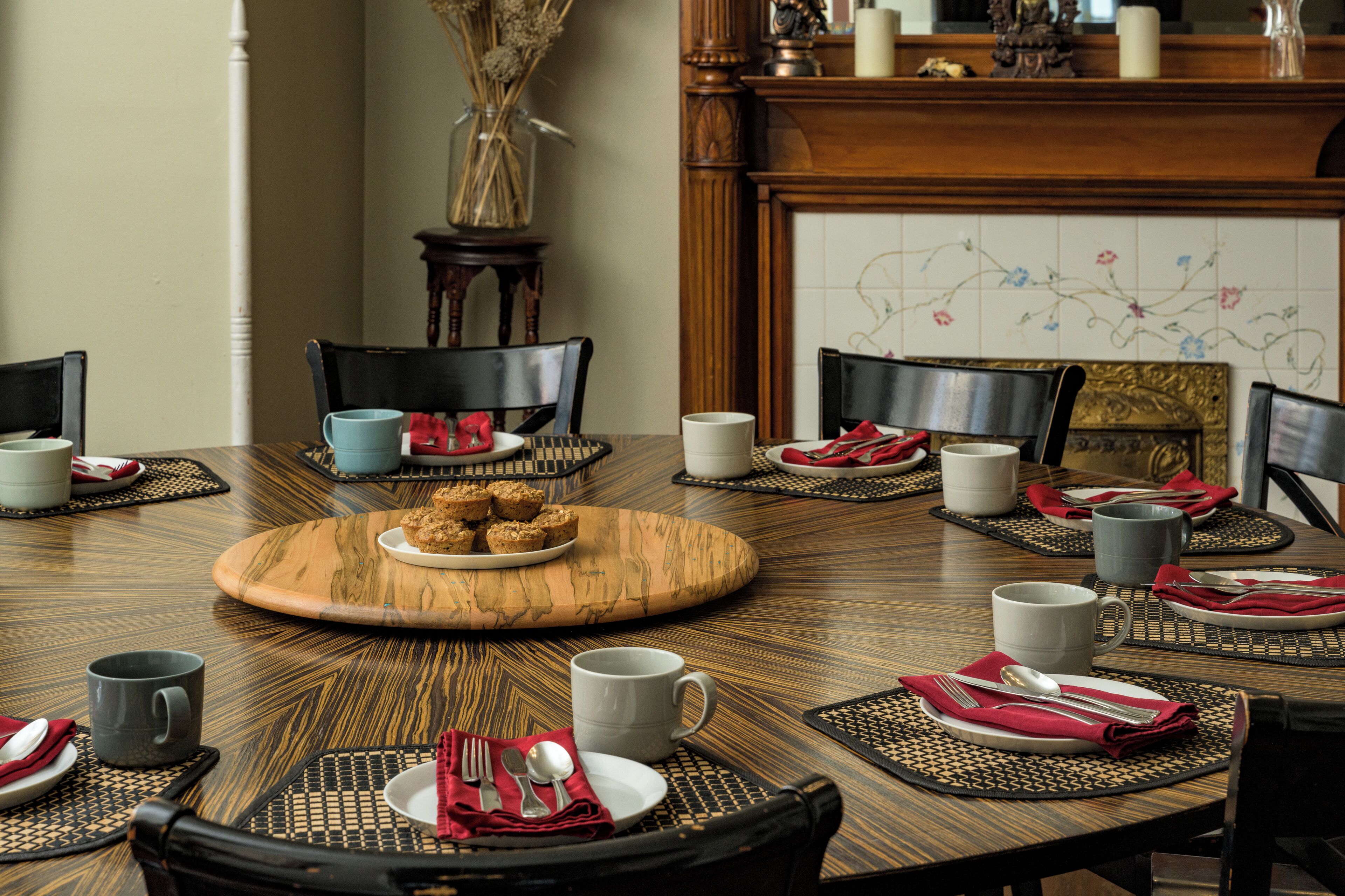 Een eettafel gedekt met borden, bestek en een serveerblik in het midden.