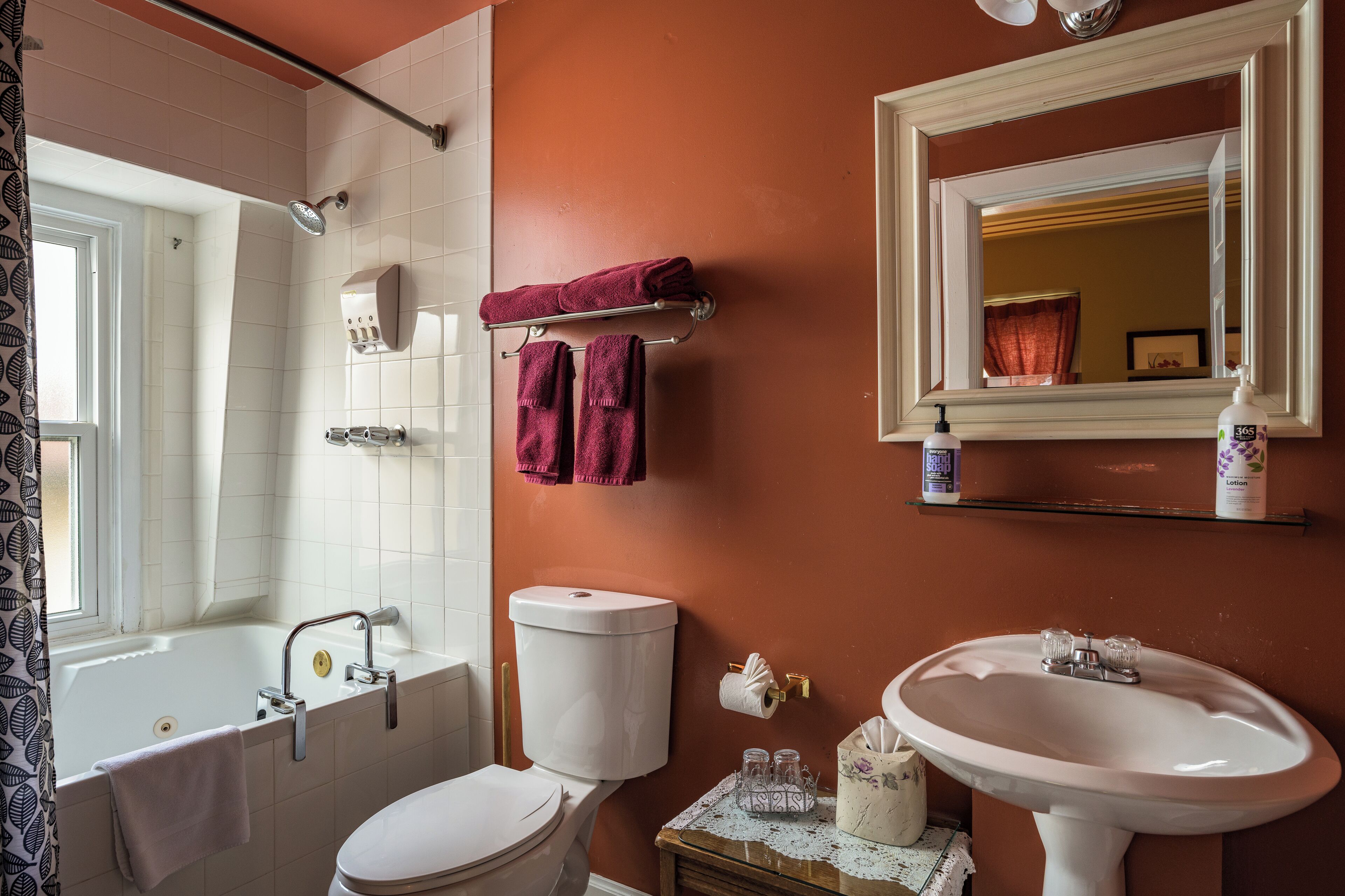 Een badkamer met een bad, toilet, wastafel en spiegel.