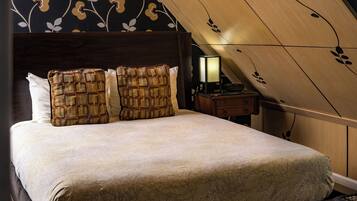A neatly made bed with patterned pillows, a bedside lamp, and a wooden headboard.