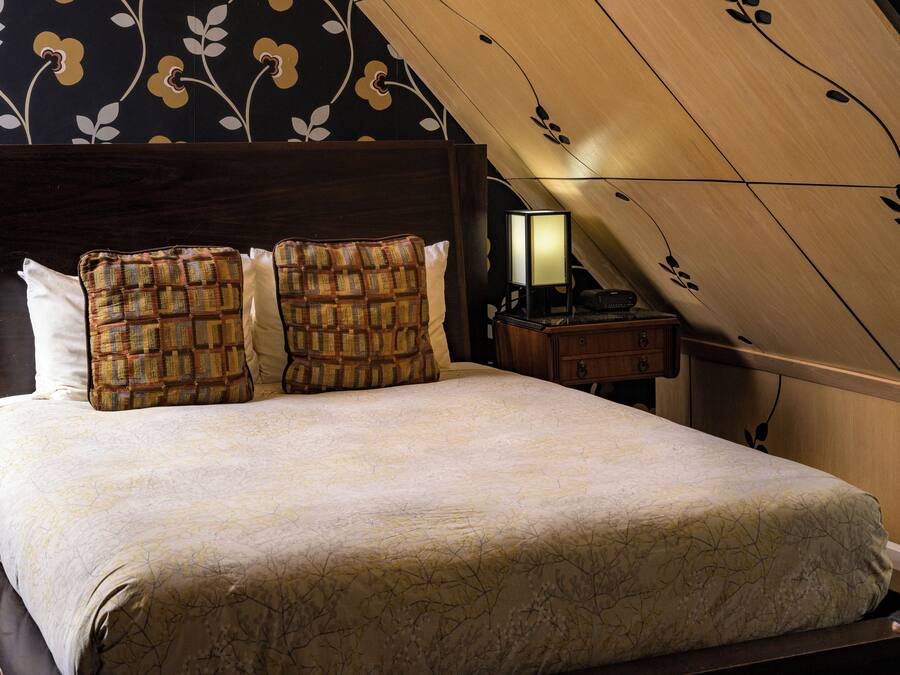 A neatly made bed with patterned pillows, a bedside lamp, and a wooden headboard.