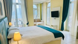 Una habitación de hotel con cama, televisión, zona de estar y ventanas amplias.