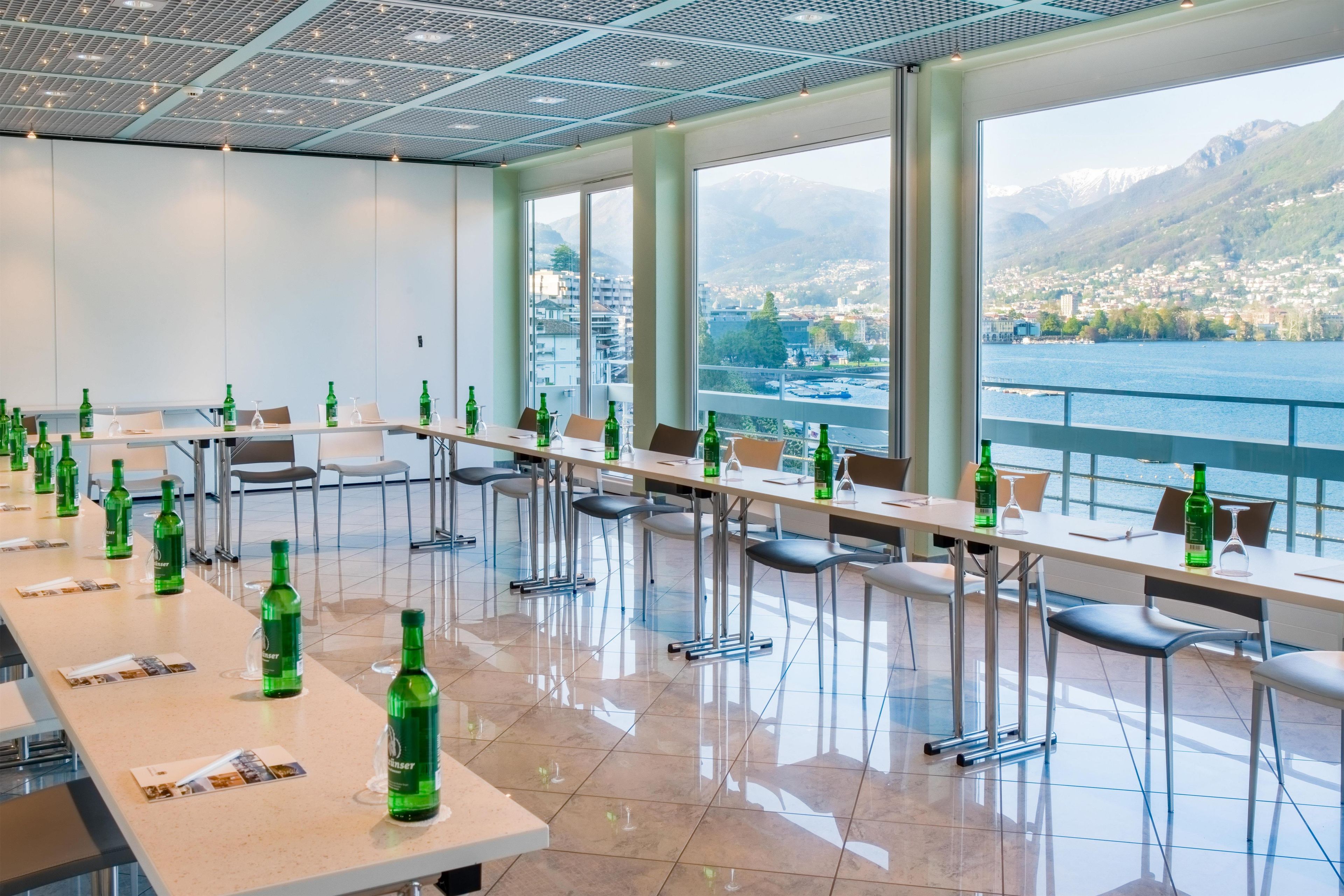 Une salle de conférence offrant une vue panoramique sur un lac et des montagnes.